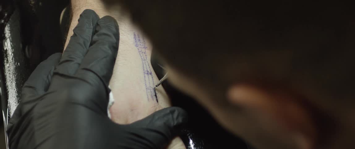 Close up of man tattooing an arm