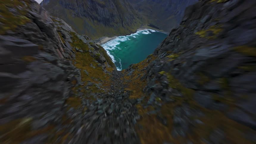 An exhilarating FPV drone dive down a rugged mountain cliff reveals a spectacular hidden beach in Norway