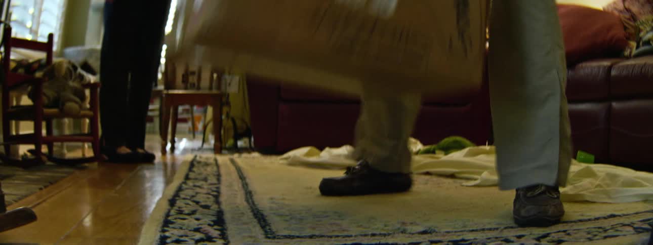 A person walks into a room and drops a box