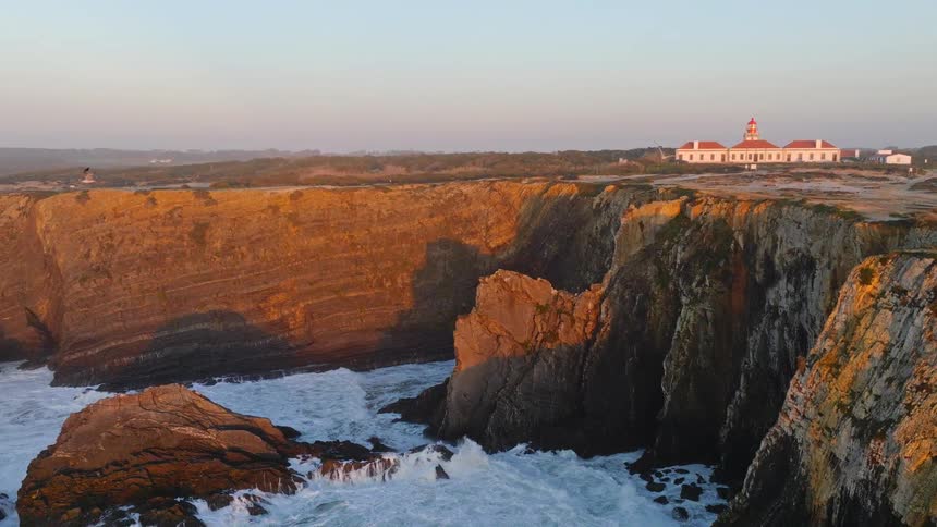 A majestic lighthouse sits atop rugged coastal cliffs bathed in the warm light of sunset as seagulls soar overhead