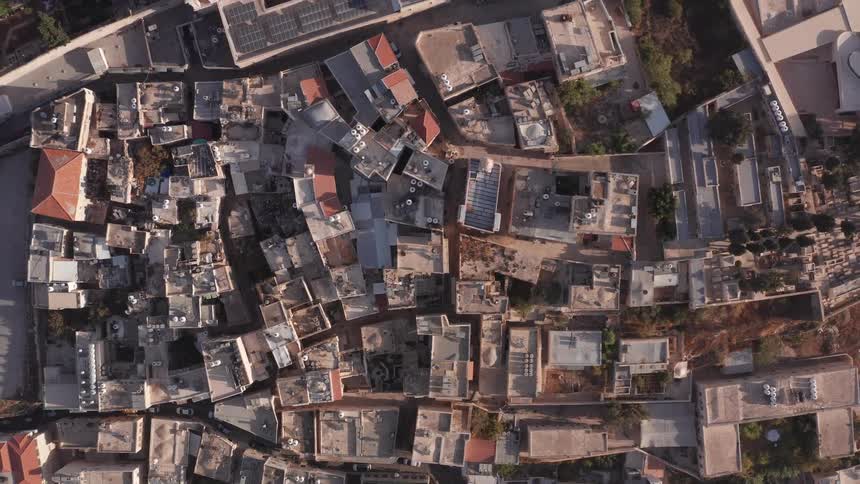 Top-down aerial view slowly ascends over the dense, ancient architecture and rooftops of a historic Middle Eastern city