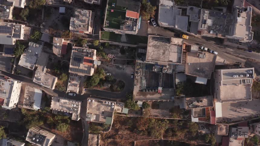 Aerial top-down drone shot slowly rises over the rooftops of a crowded Middle Eastern city