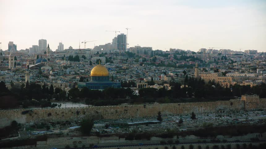 A wide shot of the iconic Dome of the Rock and the ancient city walls against the sprawling cityscape of Jerusalem