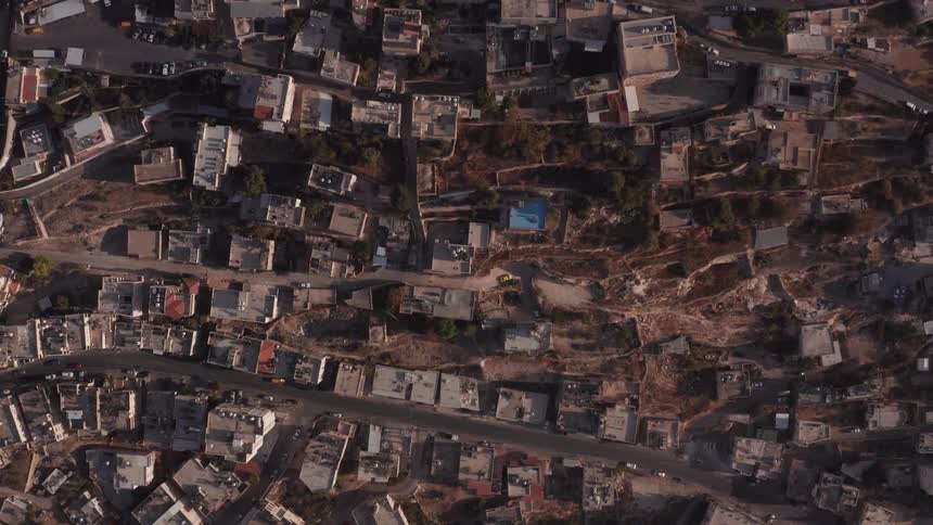 Static aerial top-down view of a dense, historic city built on a hillside with traffic moving through the streets