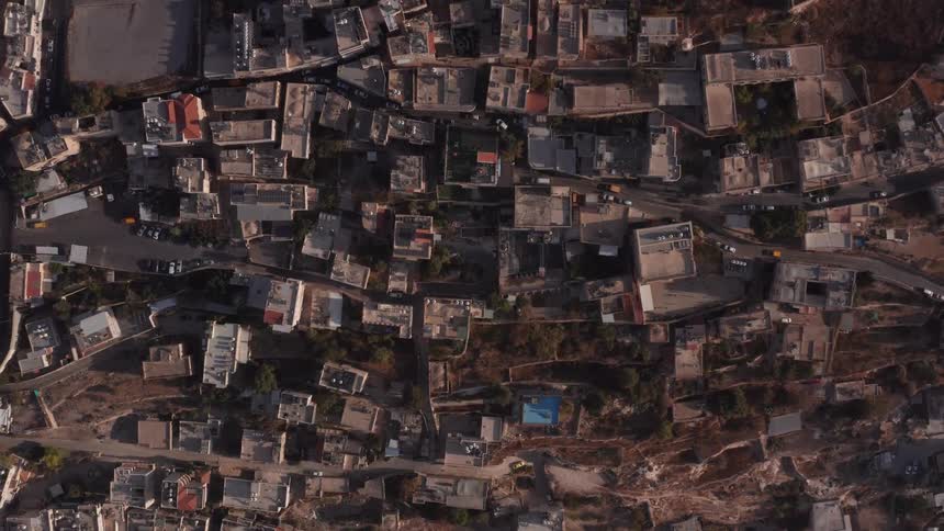 A slow-rising top-down aerial view captures the densely packed buildings and winding streets of a historic Middle Eastern city