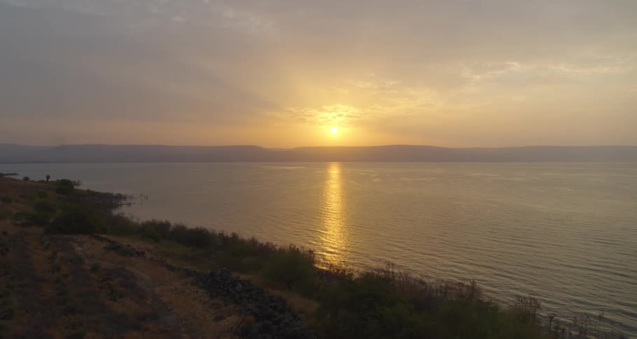 A majestic aerial view captures the golden sunrise reflecting over the calm waters of the Sea of Galilee