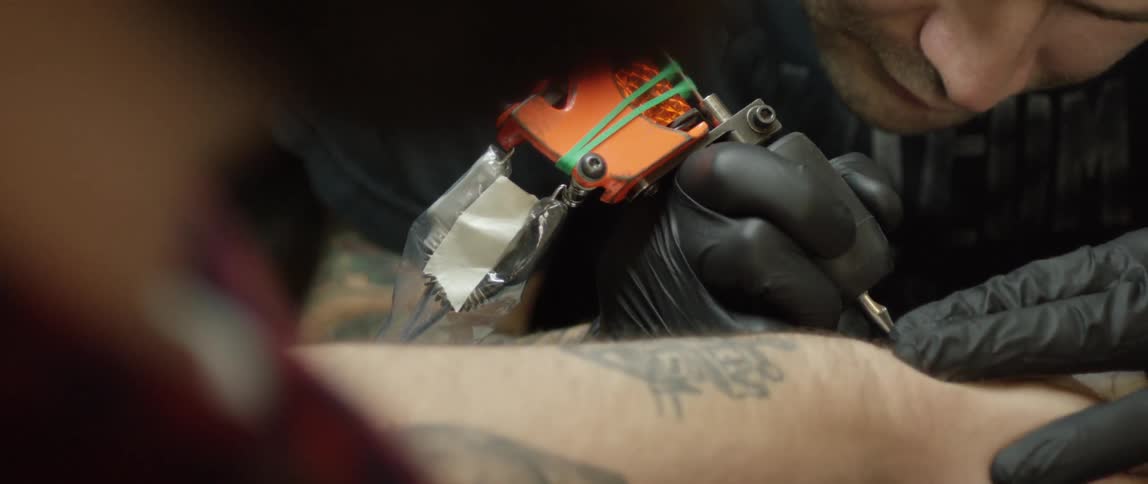 A man giving another man a tattoo