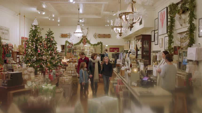 A woman holds her children's hands as they shop in a Christmas store