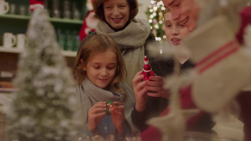 An older woman and three kids look at holiday ornaments in a shop