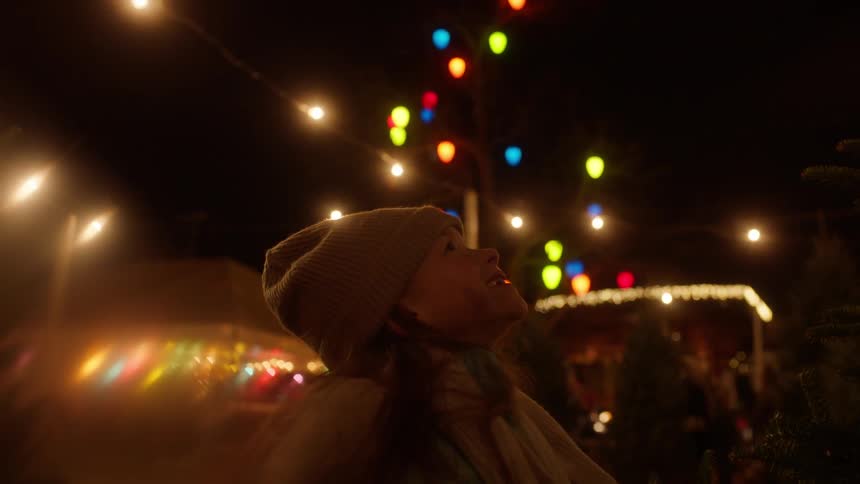 A girl looks up smiling in a tree park at night
