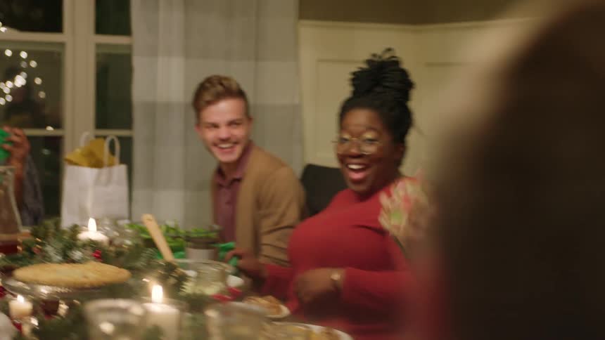 People laughing and throwing napkins at each other at christmas dinner table