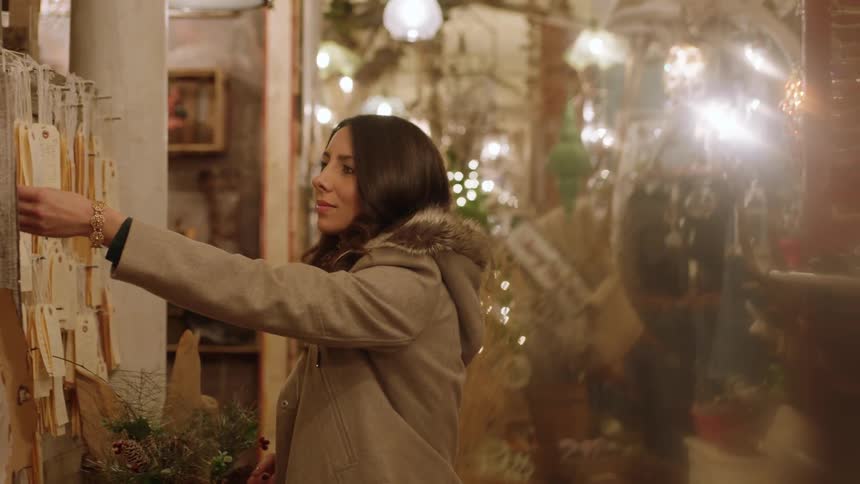 Woman looking at tags hanging on a store wall in the evening