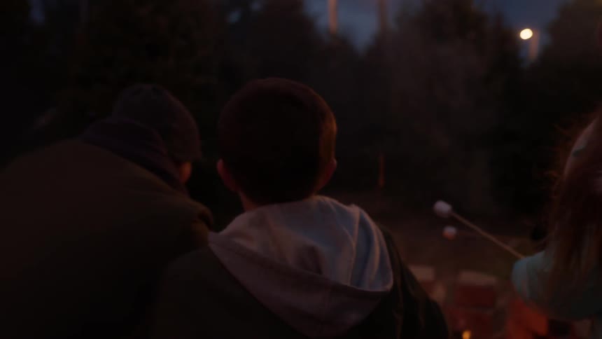 People stand around a fire at night