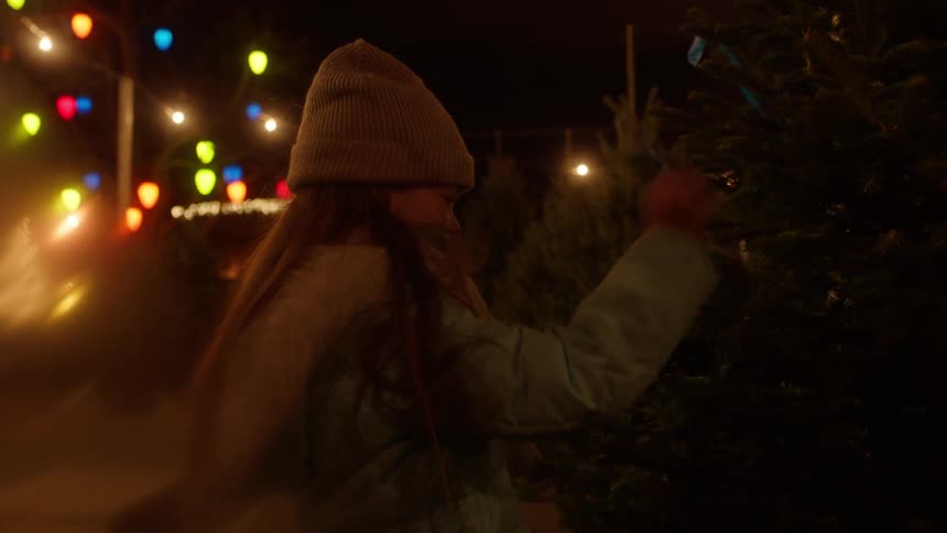 Little girl smiling while looking at christmas pine tree at night