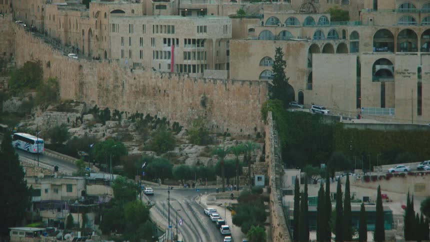 High-angle view of the Old City of Jerusalem, tilting down to reveal the ancient city walls and a modern road with traffic