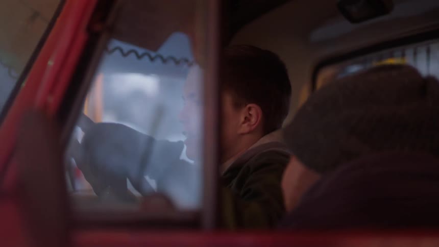 A boy sitting in the cab of a truck pretends to drive