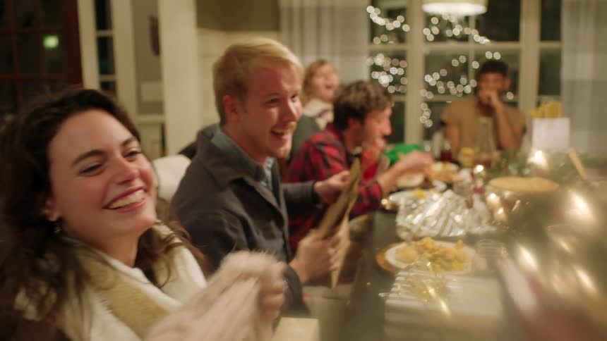 A group of people opens gifts around a dinner table