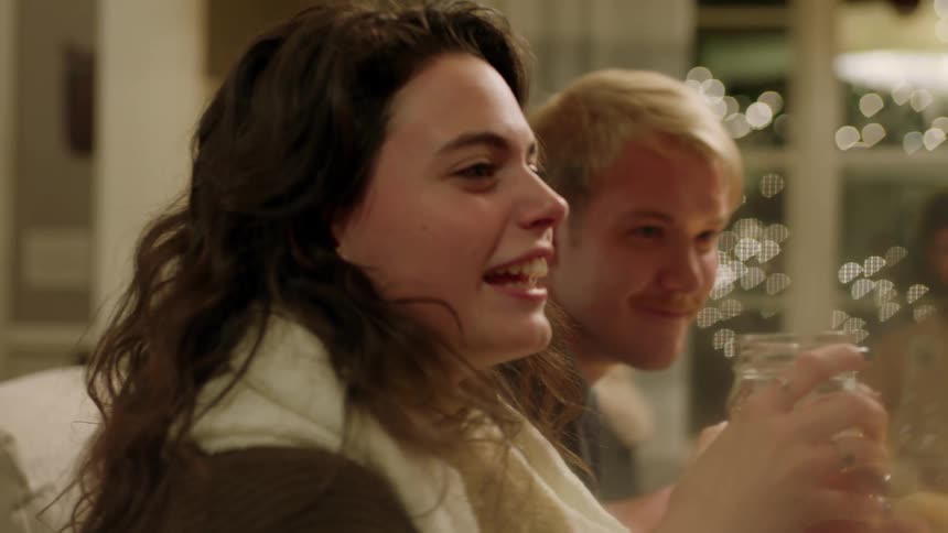A woman is talking and laughing at a dinner table with friends