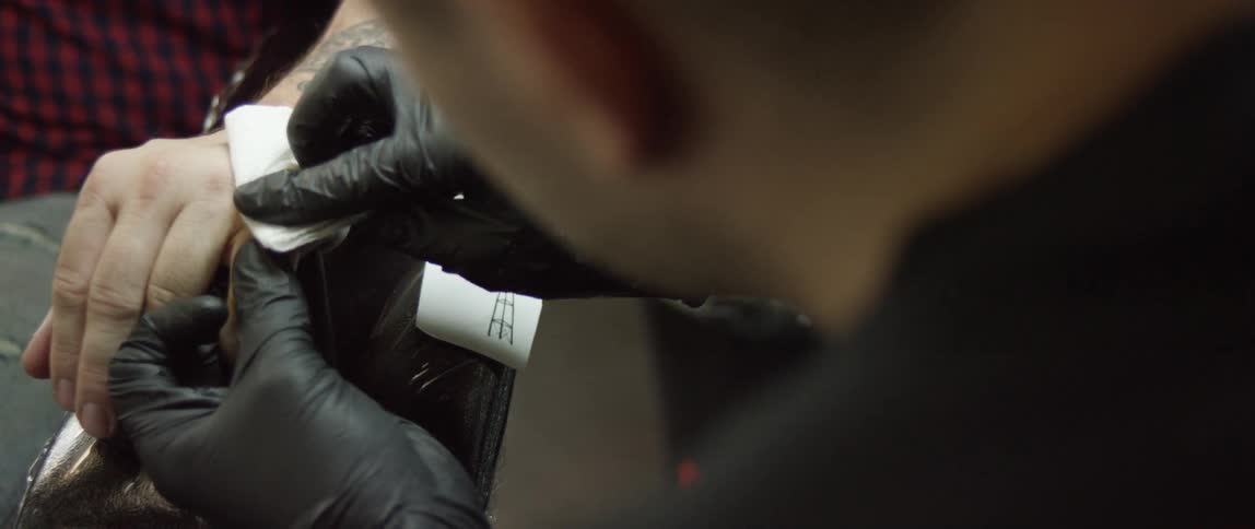 A tattoo artist wipes a new tattoo
