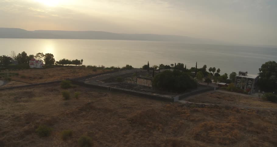 A beautiful wide shot of the ancient ruins of Capernaum on the shores of the Sea of Galilee during a hazy sunrise
