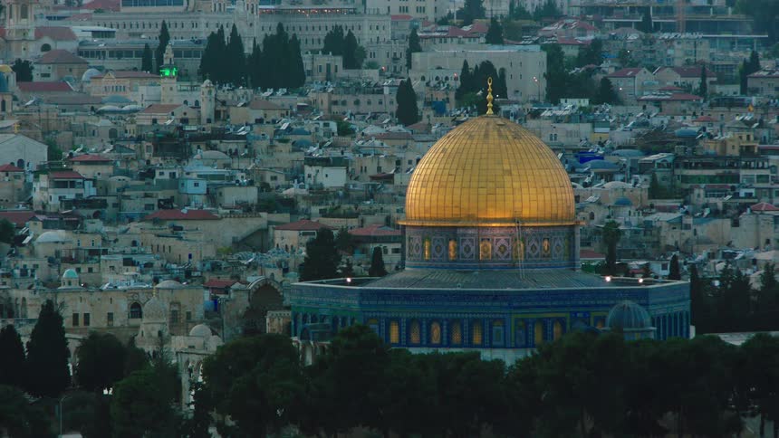 A beautiful rack focus shot reveals the iconic golden Dome of the Rock mosque in Jerusalem at dusk