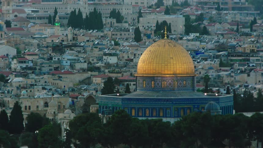 The iconic golden Dome of the Rock stands out against the sprawling cityscape of Jerusalem during twilight