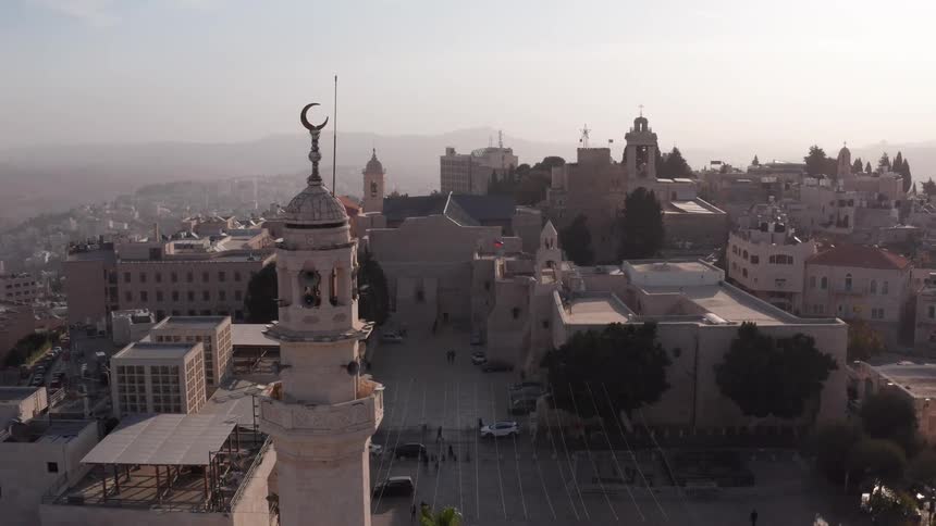 An aerial view pulls back to reveal the minaret of the Mosque of Omar with the historic Church of the Nativity in Bethlehem in the background