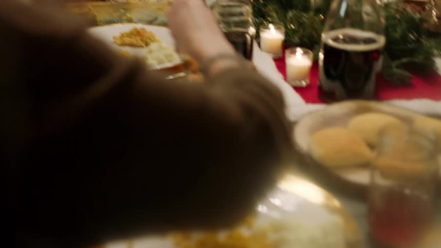 A group of people pass around food and eat at a table
