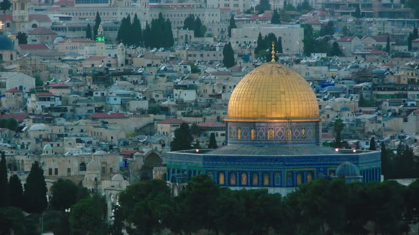 A slow zoom out from the golden Dome of the Rock in Jerusalem, revealing the surrounding Old City at twilight