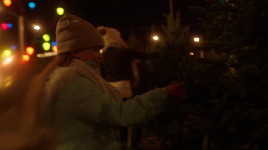 People checking out christmas tree outdoors at night in a city