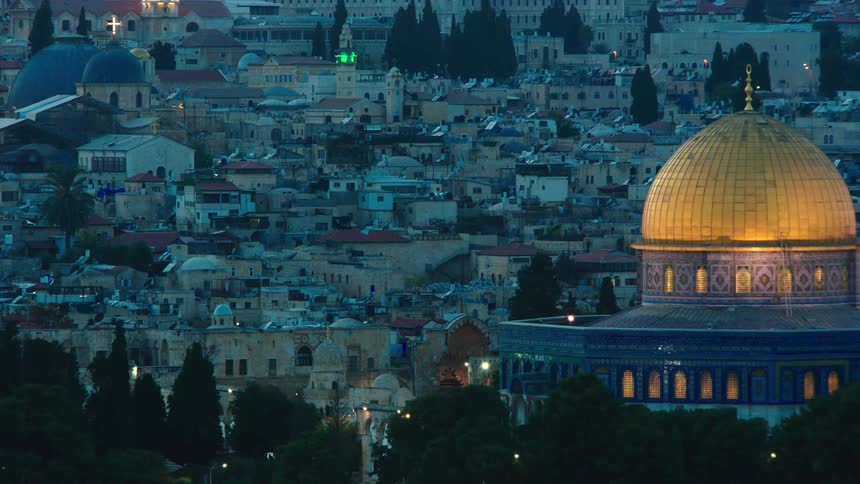 The historic cityscape of Jerusalem's Old City at twilight, featuring a slow pan to the beautifully lit Dome of the Rock