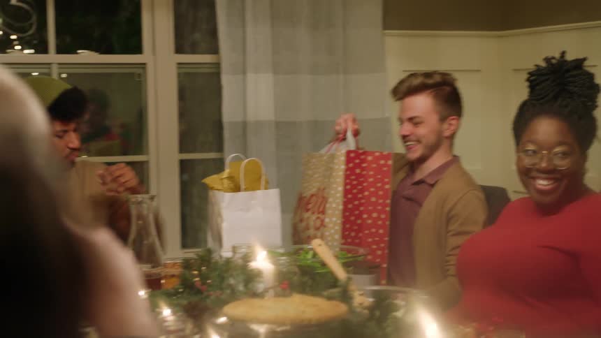 A group of people open gifts in a dining room