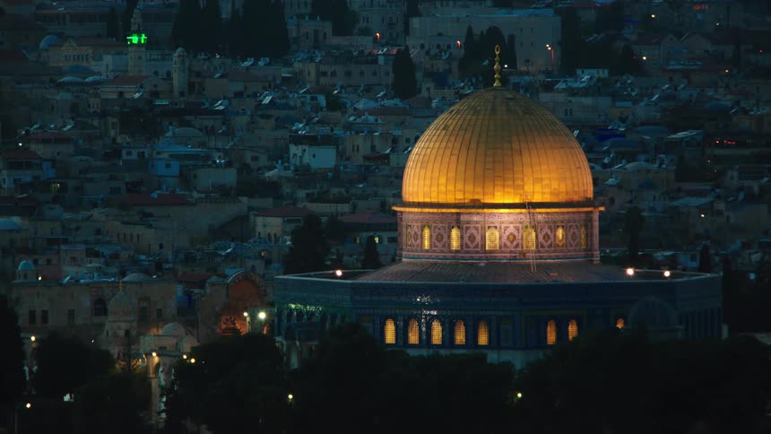 The illuminated Dome of the Rock in Jerusalem comes into focus against the night cityscape