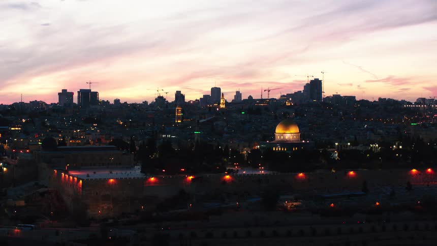 The Old City of Jerusalem, featuring the iconic Dome of the Rock, glows warmly under a colorful sunset sky