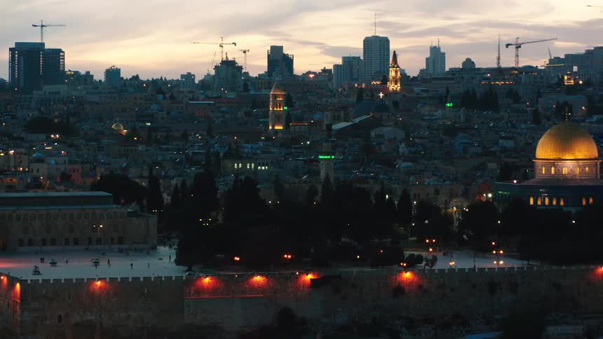 A stunning panoramic view of Jerusalem's Old City at dusk, panning from the Al-Aqsa Mosque to the brilliantly illuminated Dome of the Rock