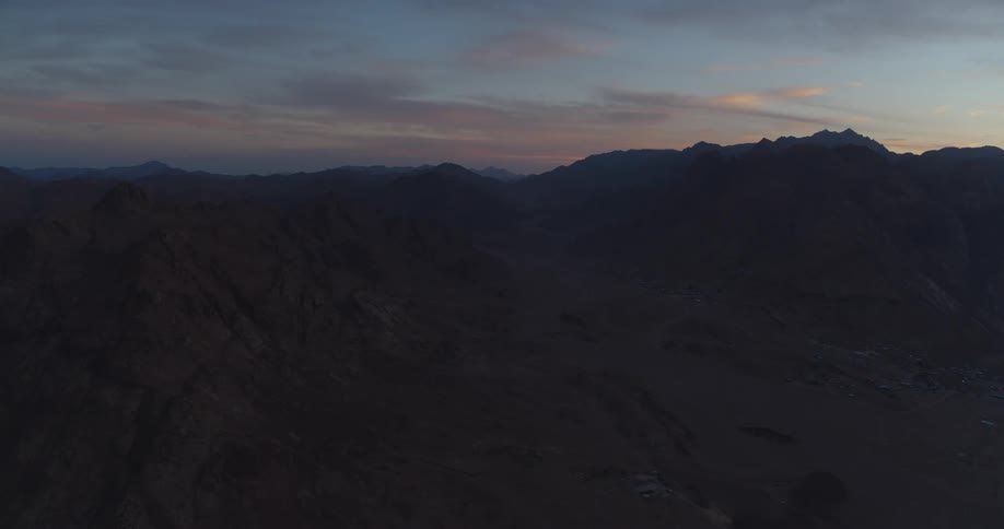 A breathtaking aerial view of a vast desert mountain range just before sunrise