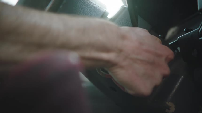 A person's hand turns the key in an old car's ignition to start the engine, shown in slow motion