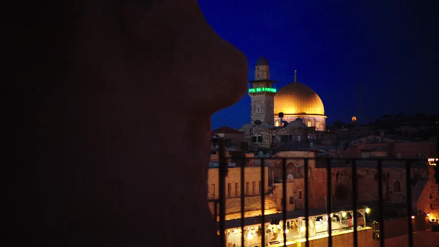 The iconic Dome of the Rock mosque shines brightly with golden lights against the deep blue night sky in Jerusalem, Israel