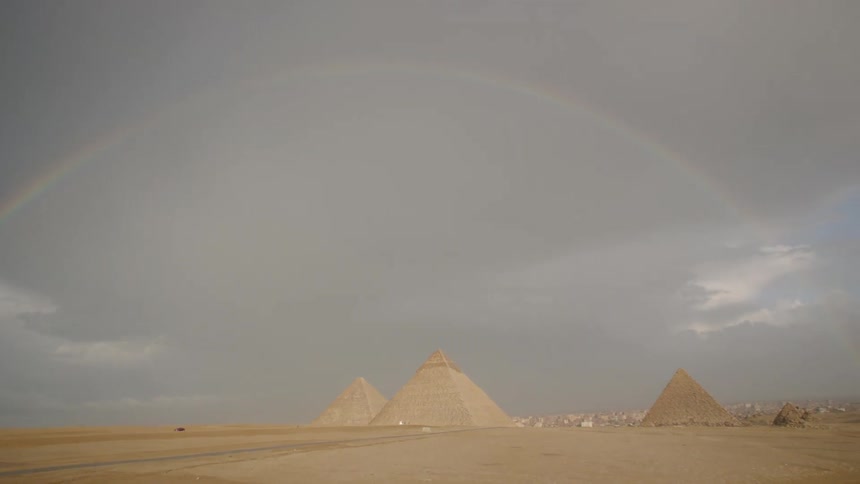 A dramatic storm sky and a beautiful rainbow arch over the Great Pyramids of Giza in the Egyptian desert