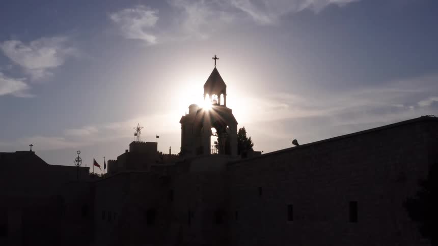 A stunning aerial view reveals the silhouette of the Church of the Nativity in Bethlehem as the bright sun rises directly behind its iconic bell tower