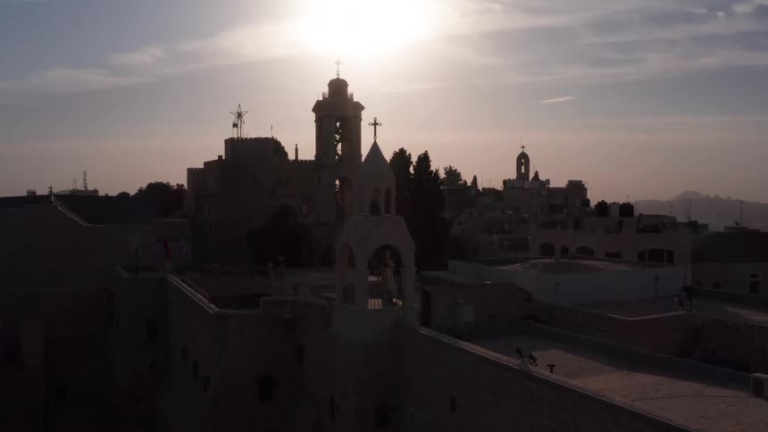 Aerial footage reveals the historic skyline and bell towers of Bethlehem silhouetted against the setting sun