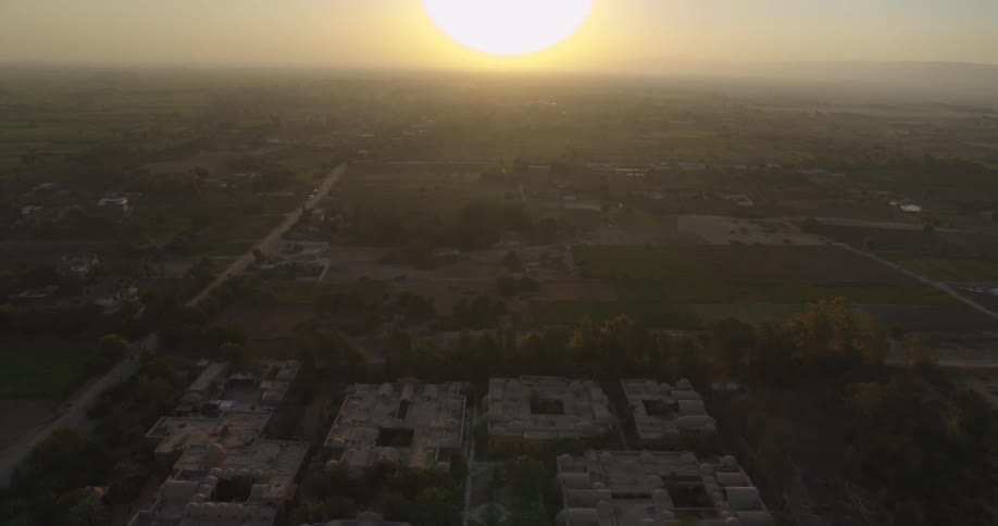 Aerial footage slowly pushes in on a unique architectural complex in a rural landscape at golden hour