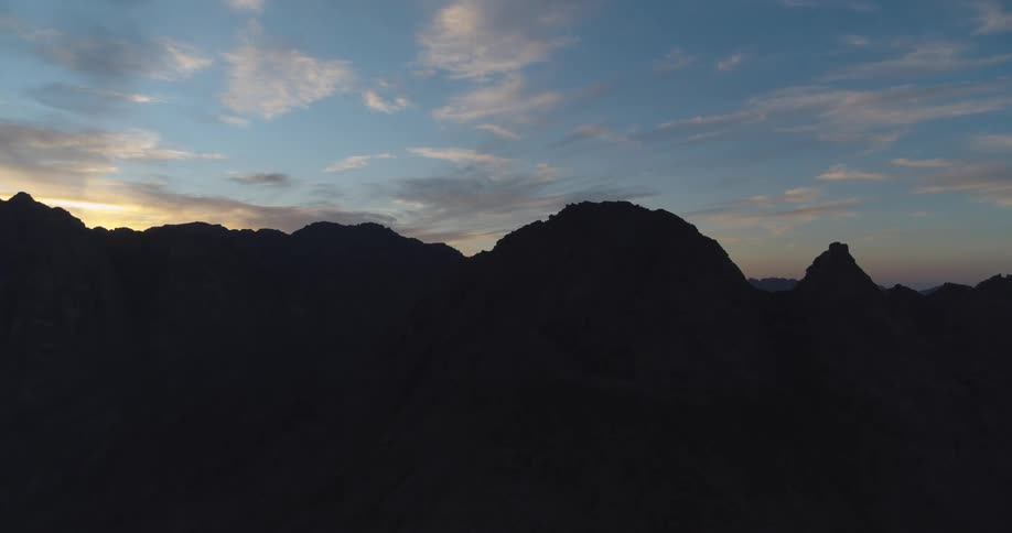 A majestic mountain range is silhouetted against the beautiful sky just before sunrise