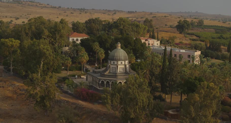 A tranquil aerial view reveals the iconic Church of the Beatitudes nestled among lush trees on a hillside in Galilee, Israel