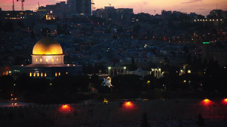 A slow rack focus from bokeh city lights reveals the iconic, golden Dome of the Rock on the Temple Mount in Jerusalem at sunset