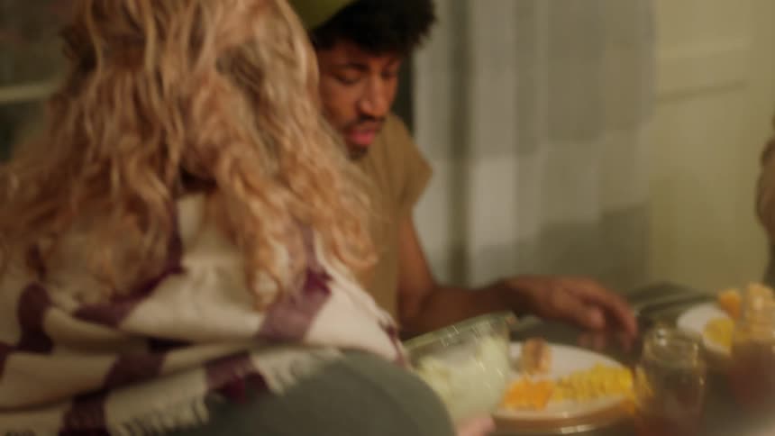 People dish up food around the dinner table