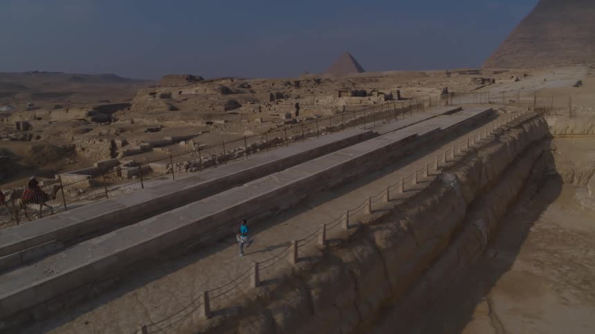 A stunning aerial shot pulls back from the Great Sphinx, revealing a man running along the ancient causeway with the pyramids on the horizon