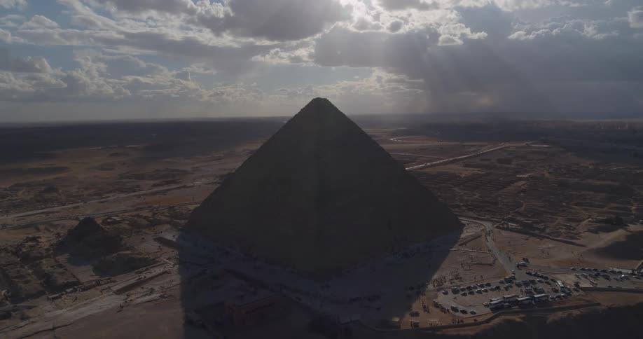 Dramatic aerial shot of the Great Pyramid of Giza as sunbeams break through the clouds over the Egyptian desert