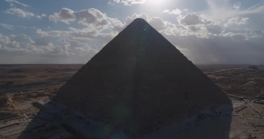 A stunning aerial view ascends to reveal the Great Pyramid of Giza silhouetted against the bright desert sun