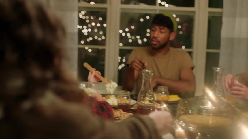 People pass buns around a table as they eat